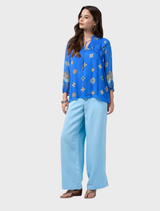 Printed blouse in azure multi with blouson sleeves, elastic cuffs, ruffled details, and a neckline secured by a glass bead tie.