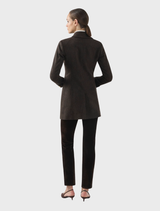 Model wearing the Delta Jacket in chocolate with gold buttons over a white turtleneck