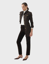 Model wearing the Delta Jacket - Chocolate with gold buttons over a white top and dark pants