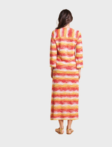 Back view of a woman in a long red dress with orange and yellow stripes, showcasing the vibrant color pattern.