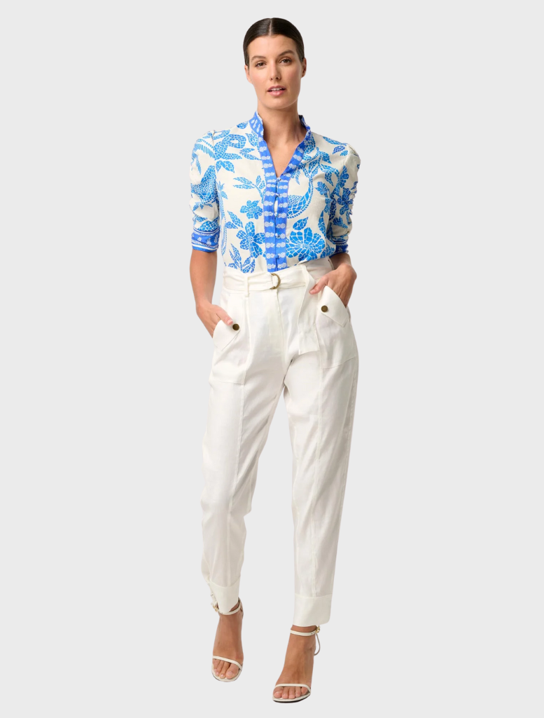 A woman in a blue and white Azure Mosaic shirt with rouched sleeves, highlighting the Calantha Viscose Dobby design.