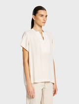 Elegant double vent top in a soft meringue hue, perfect for layering or standalone wear in various settings.