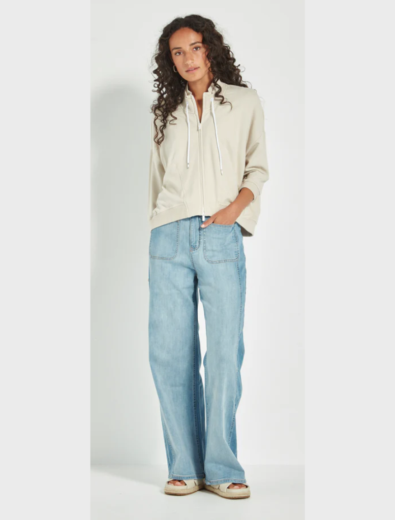 A model is seen wearing a cream sweatshirt and wide pants, exemplifying a comfortable and trendy ensemble.