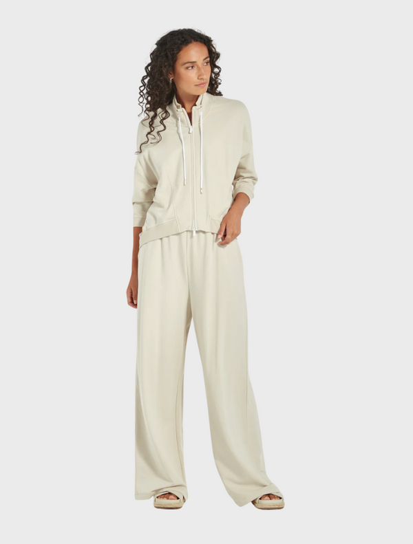 A model showcases a cream sweatshirt paired with wide pants, presenting a casual and stylish outfit.