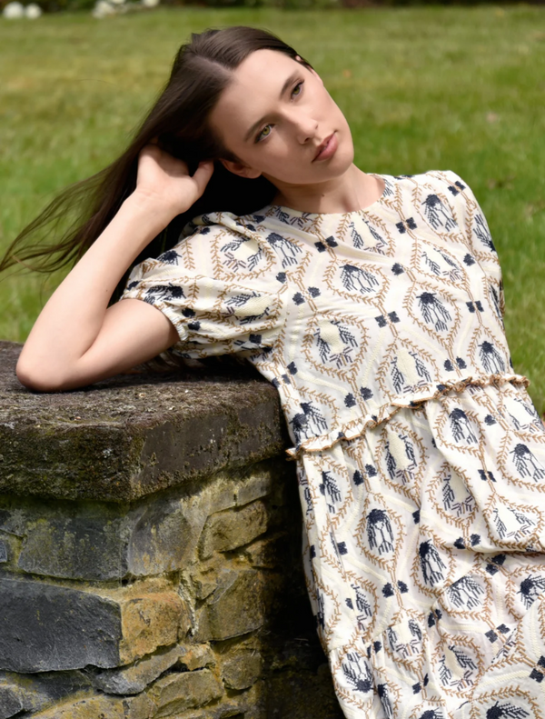  A young woman showcases a dress with a beautiful floral pattern, adding charm to her overall look.