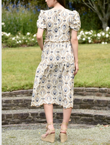 A young woman wears a dress featuring a bright floral pattern, emphasizing her fashionable and cheerful appearance.