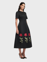 Caroline's ebony midi dress features intricate rose embellishments, ideal for adding sophistication to any wardrobe.