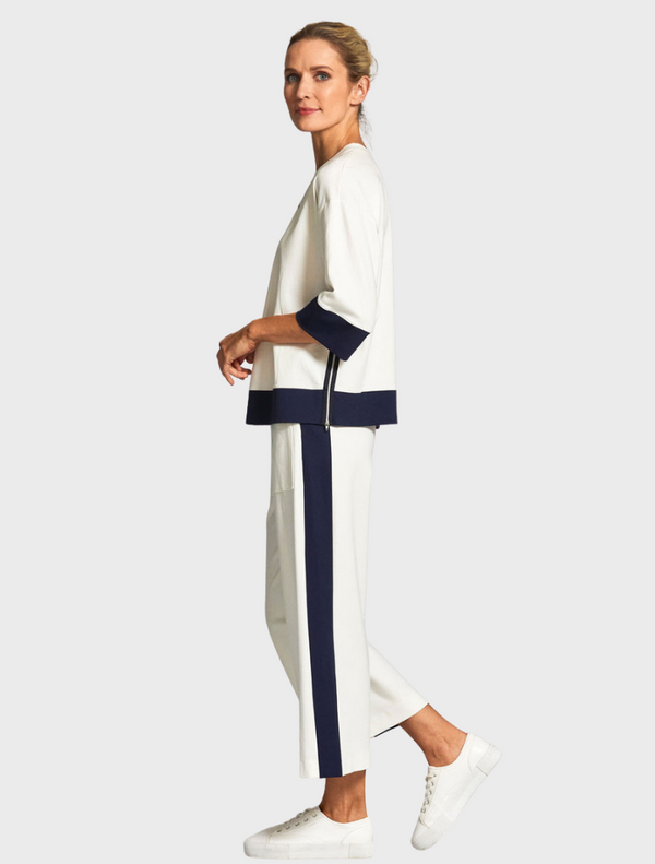The image features a model wearing a white top and navy pants, presenting a chic and contemporary look.