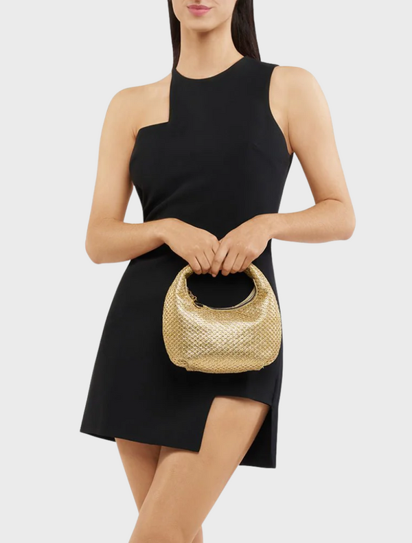 A woman in a black dress holds a gold Eden Woven Hobo bag, showcasing a stylish and elegant look.