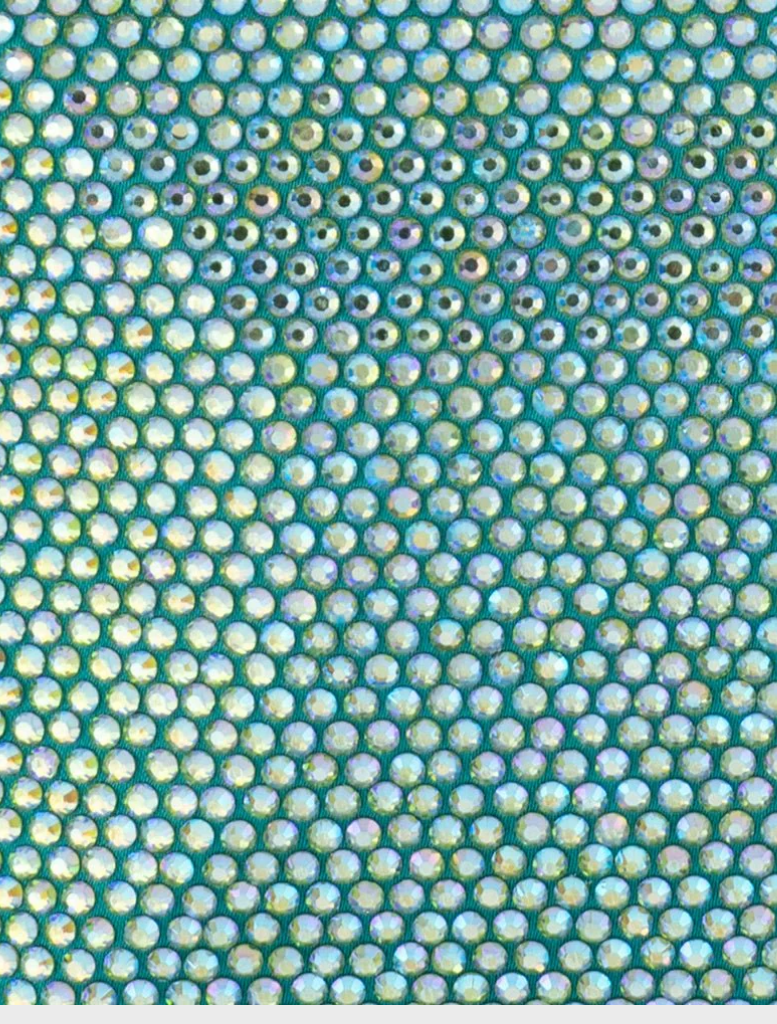 The Edith Iridescent Clutch - Green, a blue glitter bag, gracefully hanging from a chain, highlighting its sparkling texture.