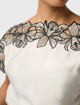 Sophisticated ivory top with cap sleeves, a broad neckline, and intricate embroidery, made from a soft cupro blend material.