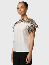 Ivory top with cap sleeves and wide neckline, featuring delicate embroidery on shoulders, made from a fluid cupro blend fabric.