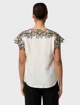 Ivory Eleanor Top characterized by a broad neckline, cap sleeves, and elaborate shoulder embroidery, constructed from a soft cupro blend fabric.