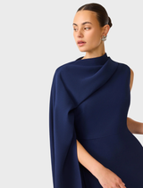 Leonara's deep navy cape dress with an asymmetric cut, ideal for sophisticated evening wear and formal gatherings.