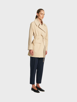 Bisque-colored wrap trench coat with a belted waist and long sleeves, offering a chic look for cooler seasons.