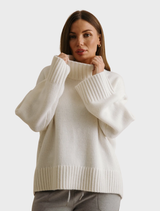 A cream-colored Elevate Mock Merino Cashmere Pullover draped on a hanger, highlighting its luxurious fabric and style.