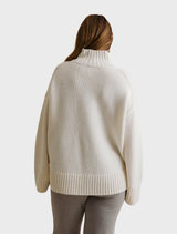 Cream Elevate Mock Merino Cashmere Pullover on a hanger, emphasizing its soft feel and chic design.
