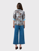 Button-through silk top in white multi, designed with shoulder shirring and contrasting prints on cuffs, placket, and collar.