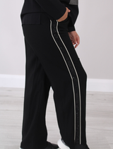 Black trousers adorned with embellished trim, designed to enhance your wardrobe with a chic flair.