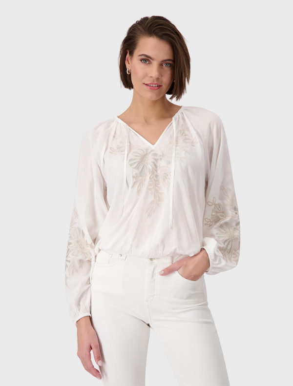 Elegant white blouse adorned with vibrant embroidered flowers, adding a touch of charm to the garment.