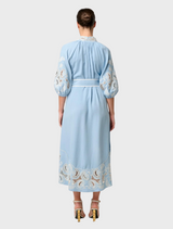 Back view of a woman in a blue maxi dress with embroidered sleeves, showcasing the Amara Tencel design in Blue Haze.