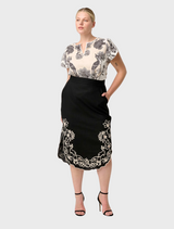 The Cascadia black midi skirt is worn by a model, highlighting its beautiful embroidered details on a flowing fabric.