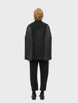 Unisex oversized black jacket in wool-blend brocade and flannel, with two front pockets and decorative cord details.