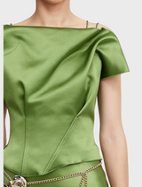 The image shows a green satin dress with a bow on the shoulder, emphasizing its fashionable and sophisticated design.