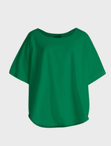 A green top stands before a tennis court, highlighting her enthusiasm for the sport.