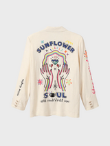 A woman showcases a white blazer with detailed embroidery, exuding style and sophistication.