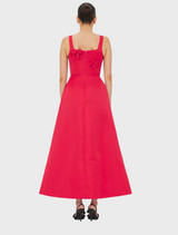 Back view of a woman in a flowing red dress, showcasing the vibrant color and elegant silhouette.