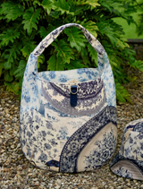 Blue FULL VOLUME Bag with circular base and drawcord closure, featuring a detachable striped strap for versatile wear.