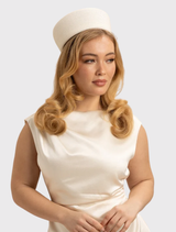 Sophisticated ivory white pillbox hat from Morgan & Taylor, perfect for racewear, with a minimalist design and secure fit.