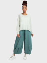 A pair of grass-green linen trousers laid flat, highlighting the texture and casual style suitable for warm weather.