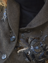 The Seam A Little Seam Jacket in a gravel hue, emphasizing its stylish cut and fabric texture, displayed on a hanger.