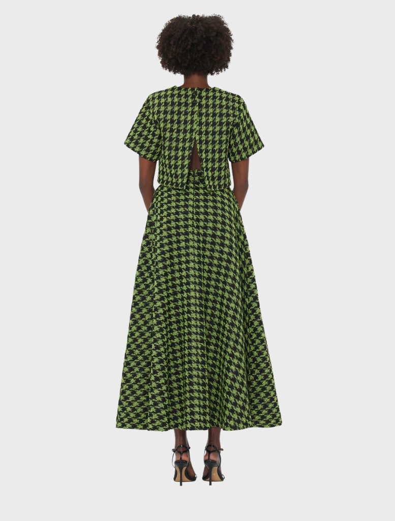Back view of a woman in a green and black checkered dress, showcasing the dress's pattern and silhouette.