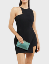 A woman in a black dress holds a green Edith Iridescent Clutch, showcasing a stylish and elegant accessory.