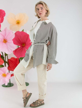 A grey Mira blouse hanging, highlighting its stylish cut and soft material.