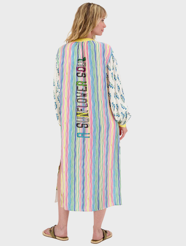 A woman models a dress adorned with bright, intricate patterns, highlighting her fashion sense and individuality.