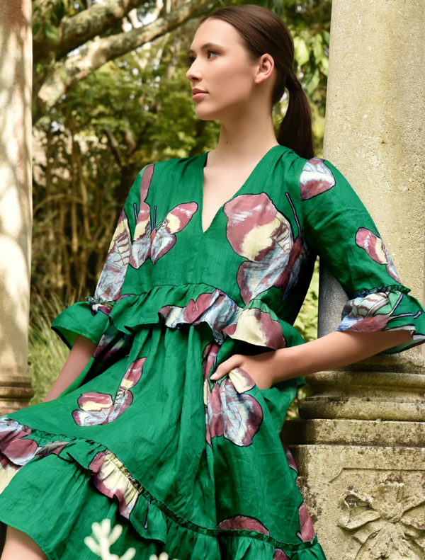 A woman in a green dress sits on a bench, enjoying a moment of relaxation in a serene outdoor setting.