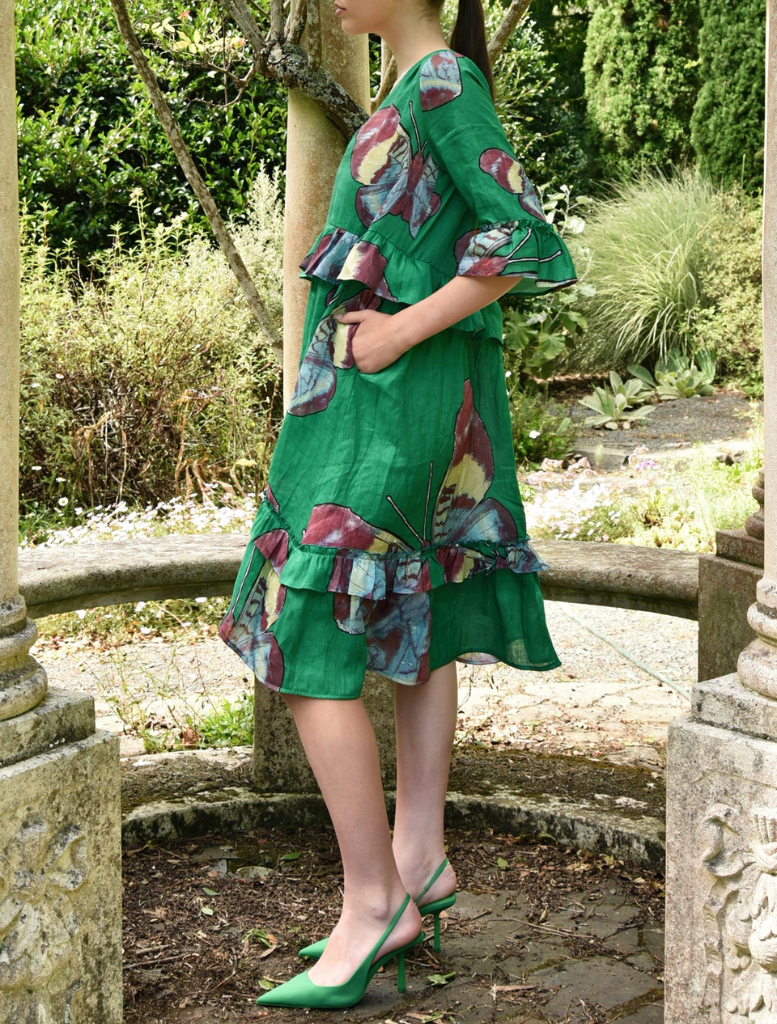 A woman in a green dress relaxes on a bench, capturing a tranquil moment in a park.