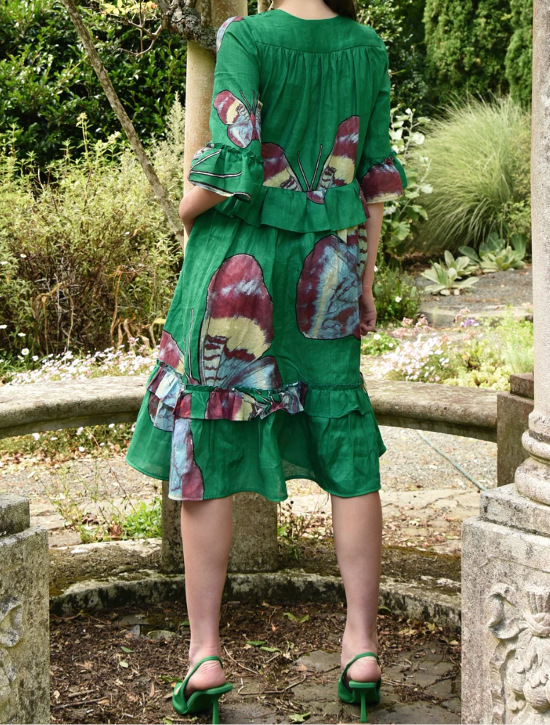  A woman dressed in green sits on a bench, immersed in her thoughts in a calm outdoor space.