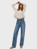 Linen shirt in white with intricate floral designs, dramatic sleeves, and a scalloped hem, reflecting a blend of modern and vintage styles.