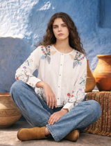 White linen shirt with floral embroidery, featuring dramatic sleeves and a scalloped hem, blending modern and heirloom styles.
