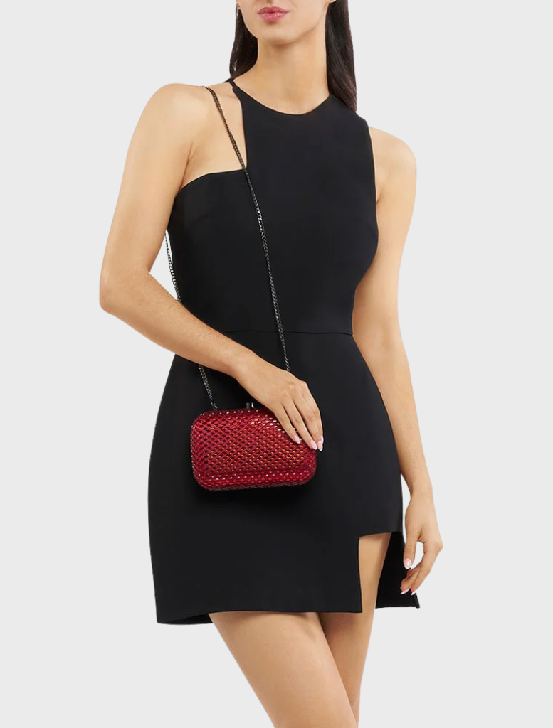 A woman wearing a black dress accessorizes with a red Brooks Hotfix clutch, exuding sophistication and style.