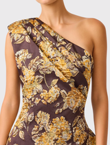 Irisa Asymmetrical Maxi Dress in brown and gold floral design, featuring a one-shoulder silhouette and tiered high-low hem.