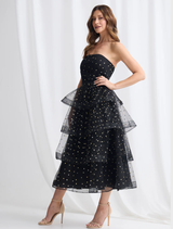 Ivana's black and gold tiered dress, highlighting its flowing design and luxurious fabric in a stylish presentation.