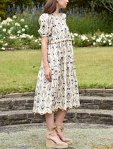 The young woman models a dress adorned with a colorful floral pattern, highlighting her stylish choice of attire.