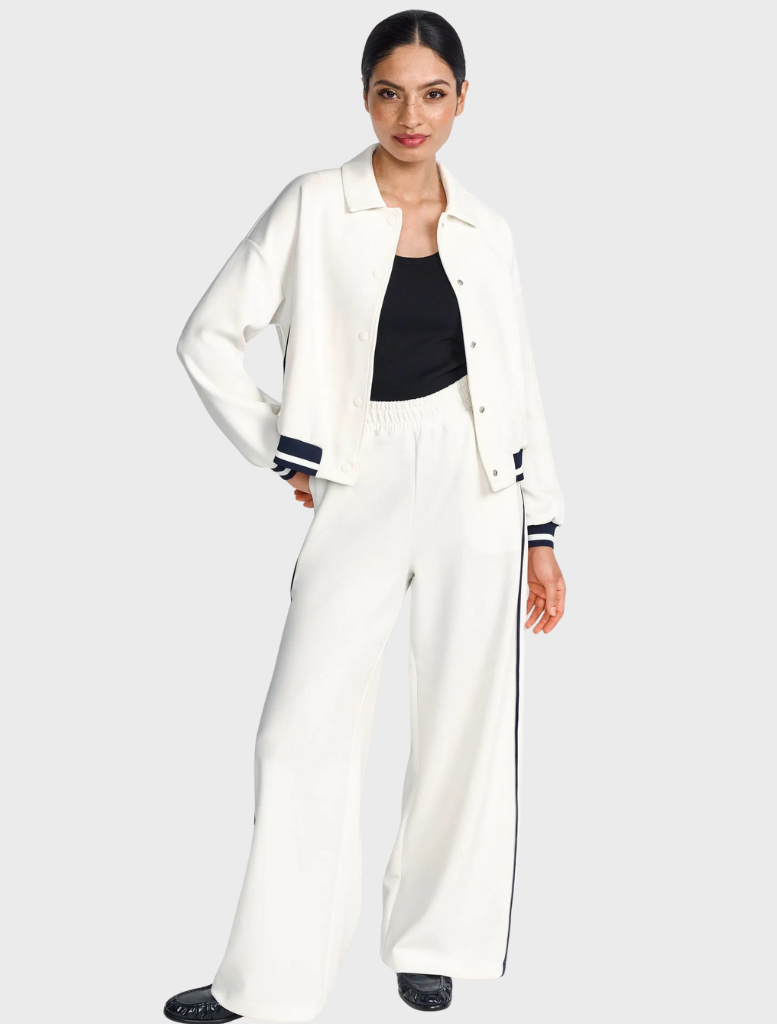 Model in a white jacket and wide pants, showcasing a stylish and modern outfit.