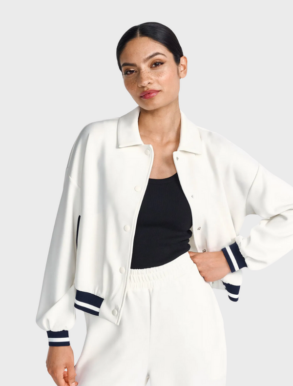 A person wearing a white and navy jacket over a black top.
